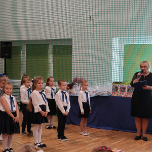 Pani Iwona Czesak rozpoczyna uroczystość pasowania na uczniów klas 1. Kliknięcie na zdjęcie spowoduje jego powiększenie do rozmiaru oryginalnego.