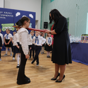 Dyrektor Joanna Ozorka-Krawczyk pasuje na ucznia uczennicę klasy 1 b. Kliknięcie na zdjęcie spowoduje jego powiększenie do rozmiaru oryginalnego.