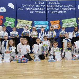 Pani Stanisława Bernady z uczniami klasy 1 b na tle dekoracji przygotowanej z okazji pasowania. Kliknięcie na zdjęcie spowoduje jego powiększenie do rozmiaru oryginalnego.