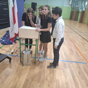 Uczniowie z Samorządu Uczniowskiego ze skrzynką przygotowaną do losowania kolorowych karteczek dzielących nauczycieli na grupy. Kliknięcie na zdjęcie spowoduje jego powiększenie do rozmiaru oryginalnego.