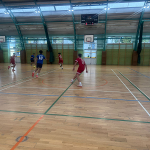 Uczniowie biegają po hali, rozgrywają mecz w ramach zawodów. Kliknięcie na zdjęcie spowoduje jego powiększenie do rozmiaru oryginalnego.