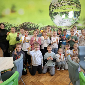 Uczniowie klas 3 prezentują świeczki wykonane na warsztatach towarzyszy im osoba prowadząca. Kliknięcie na zdjęcie spowoduje jego powiększenie do rozmiaru oryginalnego.