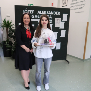 Anna Czesak z kl. 8 b  - laureatka 1 miejsca w Szkolnym Konkursie Recytatorskim Poezji Józefa Aleksandra Gałuszki z panią Dyrektor Joanną Ozorką-Krawczyk. W tle tematyczna dekoracja o poecie. Kliknięcie na zdjęcie spowoduje jego powiększenie do rozmiaru oryginalnego.