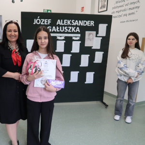 Nikola Pająk z kl. 7 a  - laureatka 1 miejsca w Szkolnym Konkursie Recytatorskim Poezji Józefa Aleksandra Gałuszki z panią Dyrektor Joanną Ozorką-Krawczyk. W tle tematyczna dekoracja o poecie. Kliknięcie na zdjęcie spowoduje jego powiększenie do rozmiaru oryginalnego.