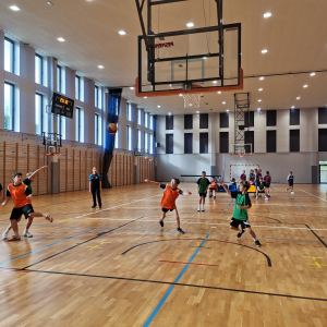 Chłopcy w trakcie grania w koszykówkę na hali gimnastycznej. Kliknięcie na zdjęcie spowoduje jego powiększenie do rozmiaru oryginalnego.