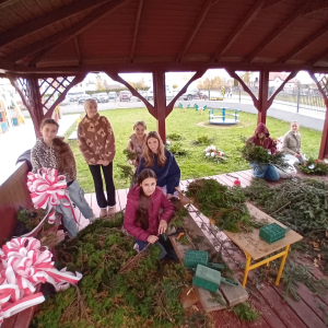 Dziewczynki z Samorządu Uczniowskiego i  Klubu Wolontariusza w altance uczą się wykonywać wiązanki. Kliknięcie na zdjęcie spowoduje jego powiększenie do rozmiaru oryginalnego.