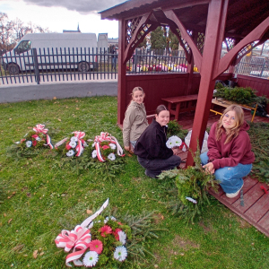 Uczennice z Samorządu Uczniowskiego oraz  Klubu Wolontariusza tworzą wiązanki w altance. Kliknięcie na zdjęcie spowoduje jego powiększenie do rozmiaru oryginalnego.