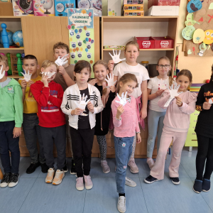 Dzieci z klas 3 a trzymają papierowe ręce wykonane na warsztatach poruszających tematykę mocnych stron. Kliknięcie na zdjęcie spowoduje jego powiększenie do rozmiaru oryginalnego.