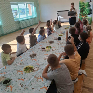 Dzieci odpowiadają na pytania zadawane przez panią prowadzącą warsztaty, zgłaszają się do odpowiedzi podnosząc ręce. Kliknięcie na zdjęcie spowoduje jego powiększenie do rozmiaru oryginalnego.