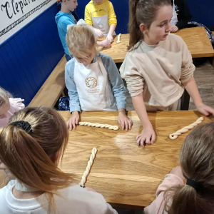 Uczennice klasy 3 b w trakcie przygotowywania warkocza na obwarzanka. Kliknięcie na zdjęcie spowoduje jego powiększenie do rozmiaru oryginalnego.