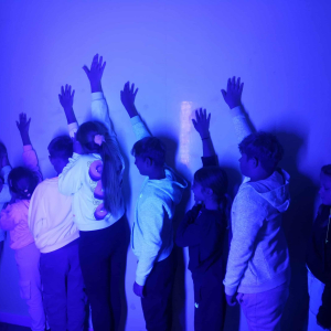 Dzieci z rękami przy ścianie w pomieszczeniu z iluzją świetlną. Kliknięcie na zdjęcie spowoduje jego powiększenie do rozmiaru oryginalnego.