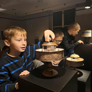 Grupka 3 chłopców z klasy 3 b przy eksponatach w Muzeum Iluzji. Kliknięcie na zdjęcie spowoduje jego powiększenie do rozmiaru oryginalnego.