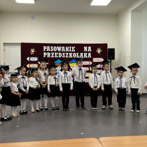 Przedszkolaki występują na pasowaniu.  Kliknięcie na zdjęcie spowoduje jego powiększenie do rozmiaru oryginalnego.