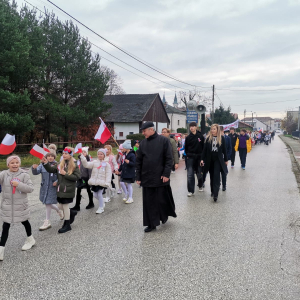 Nauczyciele, księżą i uczniowie w trakcie przemarszu z okazji Dnia Niepodległości.  Kliknięcie na zdjęcie spowoduje jego powiększenie do rozmiaru oryginalnego.