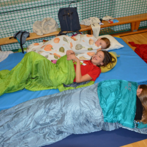 Uczennice leżą  na materacach. Dzieci nocują w szkole. Kliknięcie na zdjęcie spowoduje jego powiększenie do rozmiaru oryginalnego.