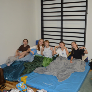 Uczennice siedzą na materacach przykryte kocem w trakcie nocnego andrzejkowego pobytu w szkole. Kliknięcie na zdjęcie spowoduje jego powiększenie do rozmiaru oryginalnego.