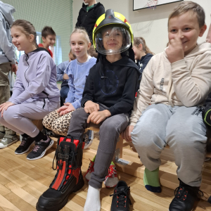 Trzecioklasista w hełmie strażackim i bucie ochronnym. Kliknięcie na zdjęcie spowoduje jego powiększenie do rozmiaru oryginalnego.