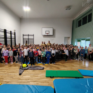 Przedszkolaki, klasy 1-3, nauczyciele i strażacy zgromadzeni na sali gimnastycznej. Kliknięcie na zdjęcie spowoduje jego powiększenie do rozmiaru oryginalnego.