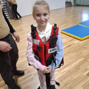 Uczennica w kamizelce ratunkowej przyniesionej przez strażaków. Kliknięcie na zdjęcie spowoduje jego powiększenie do rozmiaru oryginalnego.