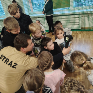 Dzieci słuchają jak należy używać jedne ze sprzętów strażackich. Kliknięcie na zdjęcie spowoduje jego powiększenie do rozmiaru oryginalnego.