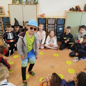 Chłopiec przebrany za turystę bierze udział w zabawach andrzejkowych. Reszta dzieci siedzi w kole, na podłodze żółte kartki. Kliknięcie na zdjęcie spowoduje jego powiększenie do rozmiaru oryginalnego.