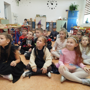 Uczniowie klasy 1 b siedzą ze skrzyżowanymi nogami. Biorą udział w klasowych andrzejkach. Kliknięcie na zdjęcie spowoduje jego powiększenie do rozmiaru oryginalnego.