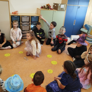 Dzieci z 1 b siedzą w kole, jedno z nich losuje wróżby andrzejkowe. Kliknięcie na zdjęcie spowoduje jego powiększenie do rozmiaru oryginalnego.