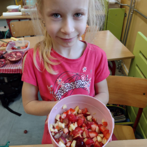 Uczennica z pokrojonymi owocami, które znajdują się w misce. Kliknięcie na zdjęcie spowoduje jego powiększenie do rozmiaru oryginalnego.