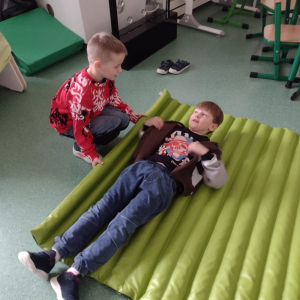 Chłopcy zawijają się w materac na zajęciach projektowych