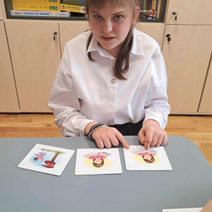 Uczennica pokazuje obrazki. Kliknięcie na zdjęcie spowoduje jego powiększenie do rozmiaru oryginalnego.