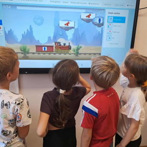 Uczniowie grają w grę multimedialną na komputerze. Kliknięcie na zdjęcie spowoduje jego powiększenie do rozmiaru oryginalnego.