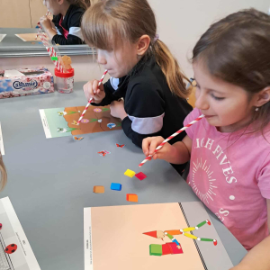 Dzieci dmuchają słomkami w karteczki. Kliknięcie na zdjęcie spowoduje jego powiększenie do rozmiaru oryginalnego.