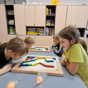 Dzieci układają na drewnianych tackach figury z drewnianych klocków. Kliknięcie na zdjęcie spowoduje jego powiększenie do rozmiaru oryginalnego.