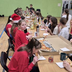 Uczniowie klas 6  jedzą pizzę w trakcie szkolnych mikołajek połączonych z nocowaniem w szkole. Kliknięcie na zdjęcie spowoduje jego powiększenie do rozmiaru oryginalnego.