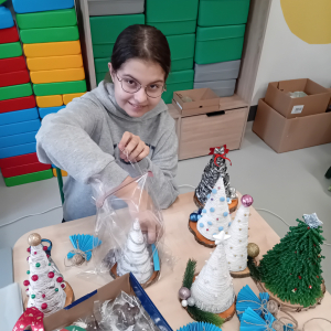 Wolontariuszka pakuje wszystkie upominki - choinkę, aniołka, pierniczka. Kliknięcie na zdjęcie spowoduje jego powiększenie do rozmiaru oryginalnego.