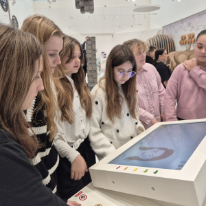 Grupka uczennic z klasy 7 przy interaktywnym ekranie w Małopolskim Centrum Cogiteon. Kliknięcie na zdjęcie spowoduje jego powiększenie do rozmiaru oryginalnego.