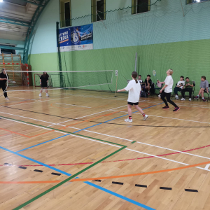 Uczestnicy Mikołajkowego Turnieju w Badmintona przebijają lotkę nad siatką. Kliknięcie na zdjęcie spowoduje jego powiększenie do rozmiaru oryginalnego. 