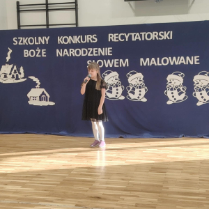 Kaja Śledź z kl. 1 b - laureatka 2 miejsca w trakcie prezentacji swojego wiersza. Kliknięci na zdjęcie spowoduje jego powiększenie do rozmiaru oryginalnego. 