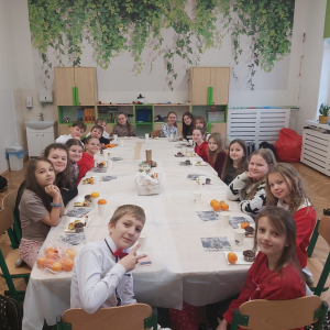 Uczniowie klasy 4 b siedzą przy stole w trakcie klasowej Wigilii. Kliknięcie na zdjęcie spowoduje jego powiększenie do rozmiaru oryginalnego.