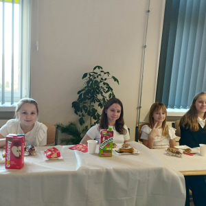 Uczniowie klasy 5 b siedzą przy stołach w trakcie klasowej Wigilii. Kliknięcie na zdjęcie spowoduje jego powiększenie do rozmiaru oryginalnego.