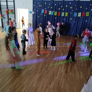 Uczniowie przebrani w kolorowe stroje tańczą na zabawie karnawałowej. Kliknięcie na zdjęcie spowoduje jego powiększenie do rozmiaru oryginalnego.