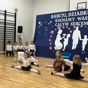 Grupka dziewczynek z oddziału przedszkolnego prezentuje szpagaty.  Kliknięcie na zdjęcie spowoduje jego powiększenie do rozmiaru oryginalnego.