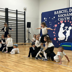 Przedszkolaki prezentują piramidę gimnastyczną dziadkom na występie.  Kliknięcie na zdjęcie spowoduje jego powiększenie do rozmiaru oryginalnego.