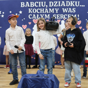 Uczniowie w słuchawkach i z magnetofonem występują dla dziadków.  Kliknięcie na zdjęcie spowoduje jego powiększenie do rozmiaru oryginalnego.