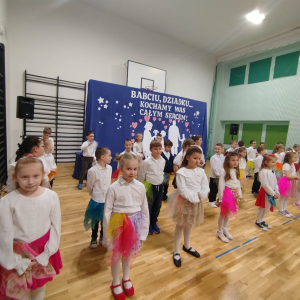 Uczniowie klas 1 z kolorowymi chustami w trakcie występuj z okazji Dnia Babci i Dziadka. Kliknięcie na zdjęcie spowoduje jego powiększenie do rozmiaru oryginalnego.