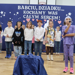 Jedna z dziewczynek prezentuje wiersz z okazji Dnia Babci i Dziadka.  Kliknięcie na zdjęcie spowoduje jego powiększenie do rozmiaru oryginalnego.