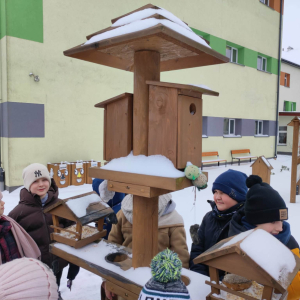 Dzieci wkładają ziarna dla ptaków do karmnika. Kliknięcie na zdjęcie spowoduje jego powiększenie do rozmiaru oryginalnego.