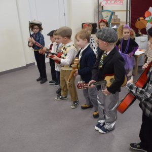 Grupka przedszkolaków gra na gitarach w trakcie występu z okazji Dnia Babci i Dziadka. Kliknięcie na zdjęcie spowoduje jego powiększenie do rozmiaru oryginalnego.