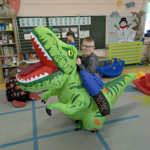Chłopiec siedzi na dinozaurze. Kliknięcie na zdjęcie spowoduje jego powiększenie do rozmiaru oryginalnego.