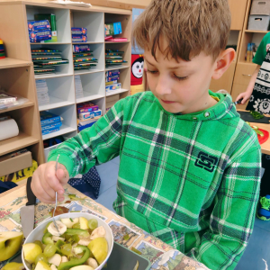 Uczeń klasy 3 a w trakcie przygotowywania posiłku z wykorzystaniem zielonych owoców i warzyw. Kliknięcie na zdjęcie spowoduje jego powiększenie do rozmiaru oryginalnego.